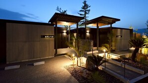 A modern house with a covered patio, a stone wall, and a small garden with plants and a rock. - SIOKUMIHAMA  Sea  Side  Villa  HAMATSUZURI (Miyazu)
