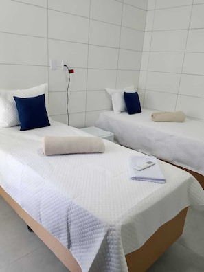 Een hotelkamer met twee bedden, witte beddengoed en een klein tafeltje met een telefoon en een handdoek.