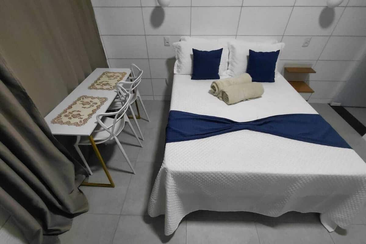 Ein Hotelzimmer mit einem Bett, einem Tisch mit Stühlen und einem Fenster mit Vorhängen.
