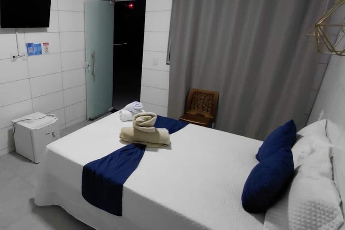 Ein Hotelzimmer mit einem Bett, einem Schreibtisch, einem Stuhl, einem Kleiderschrank und einem Fernseher.