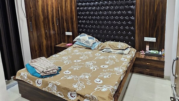 Een slaapkamer met een groot bed, houten wanden, een plafondventilator en een nachtkastje.
