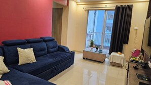 Een woonkamer met een blauwe bank, een bijzettafeltje en een balkon met uitzicht.