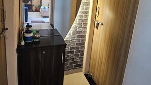 Een gang met een houten deur, een stenen muur en een kleine keuken met kastjes en een aanrecht.