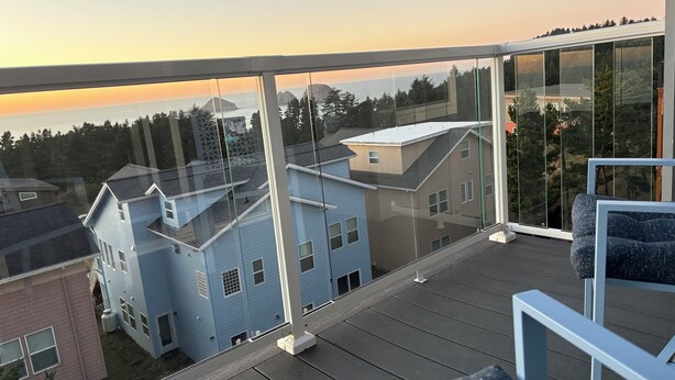 A balcony with a clear view of neighboring houses and a sunset. - Hill top Oceanside Escape--30+days minimum! (Tillamook)
