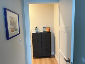 Ein Flur mit einem schwarzen Aktenschrank, einem gerahmten Bild an der Wand und einer Tür rechts.