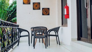 A balcony with three chairs, a table, and two wall-mounted artworks. - Lovely 2-bedroom apartment in vibrant Kigali perfect for your stay (Kigali)