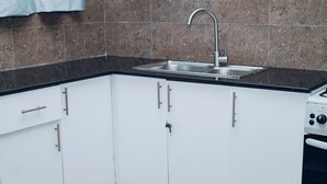 A kitchen with white cabinets, a stainless steel sink, and a stove. - Lovely 2-bedroom apartment in vibrant Kigali perfect for your stay (Kigali)