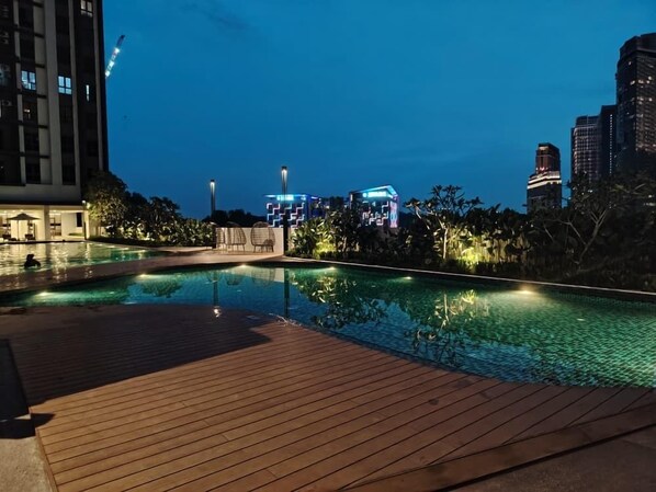 Una piscina con un pontile in legno, circondata da edifici e vegetazione.