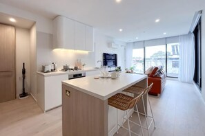 Une cuisine moderne dotée d’un îlot central, de tabourets de bar et offrant une vue sur la ville.