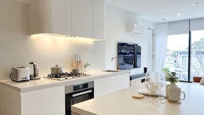 Een moderne keuken met een centraal eiland, inbouwapparatuur en een groot raam met uitzicht.