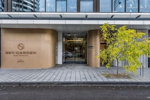 L’entrée d’un hôtel, avec une grande enseigne indiquant « SKY GARDEN » et un arbre devant.
