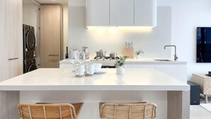 Een moderne keuken met een centraal eiland, witte kasten en een ingebouwde wasmachine.