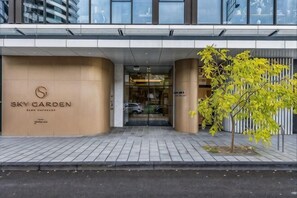 Der Eingangsbereich eines Hotels mit modernem Design, inklusive großem Logo und Glastür.