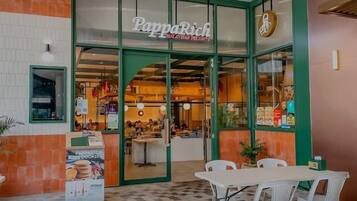 A restaurant named PappaRich with a green exterior and a checkered floor pattern.