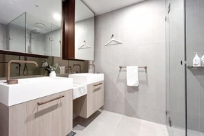 A modern bathroom with two sinks, a large mirror, and a glass shower enclosure. - Modern Luxury 2B2B Sky Garden SmartTV (Glen Waverley)