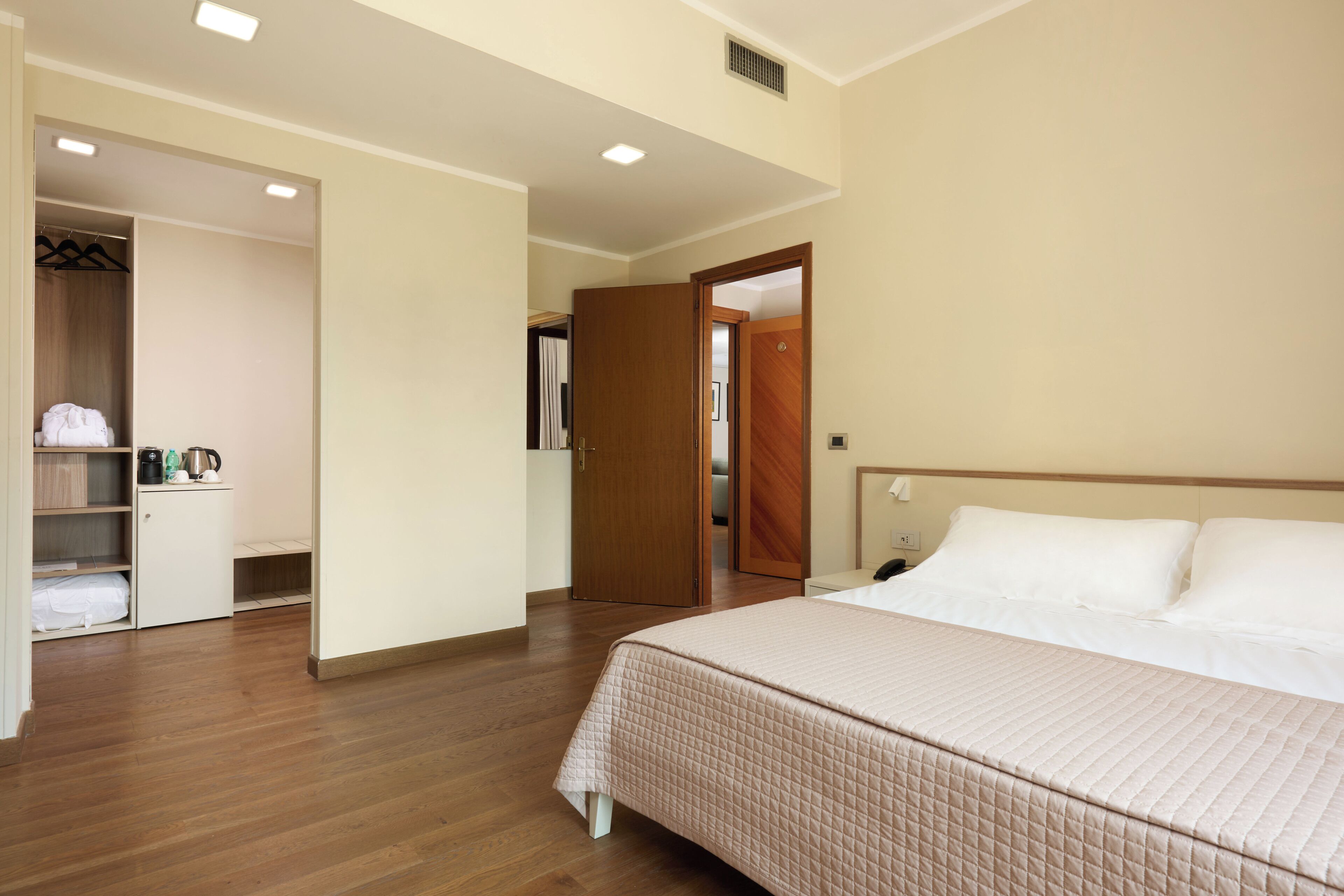 Ein Hotelzimmer mit Bett, Kleiderschrank, Bad und Duschbereich.