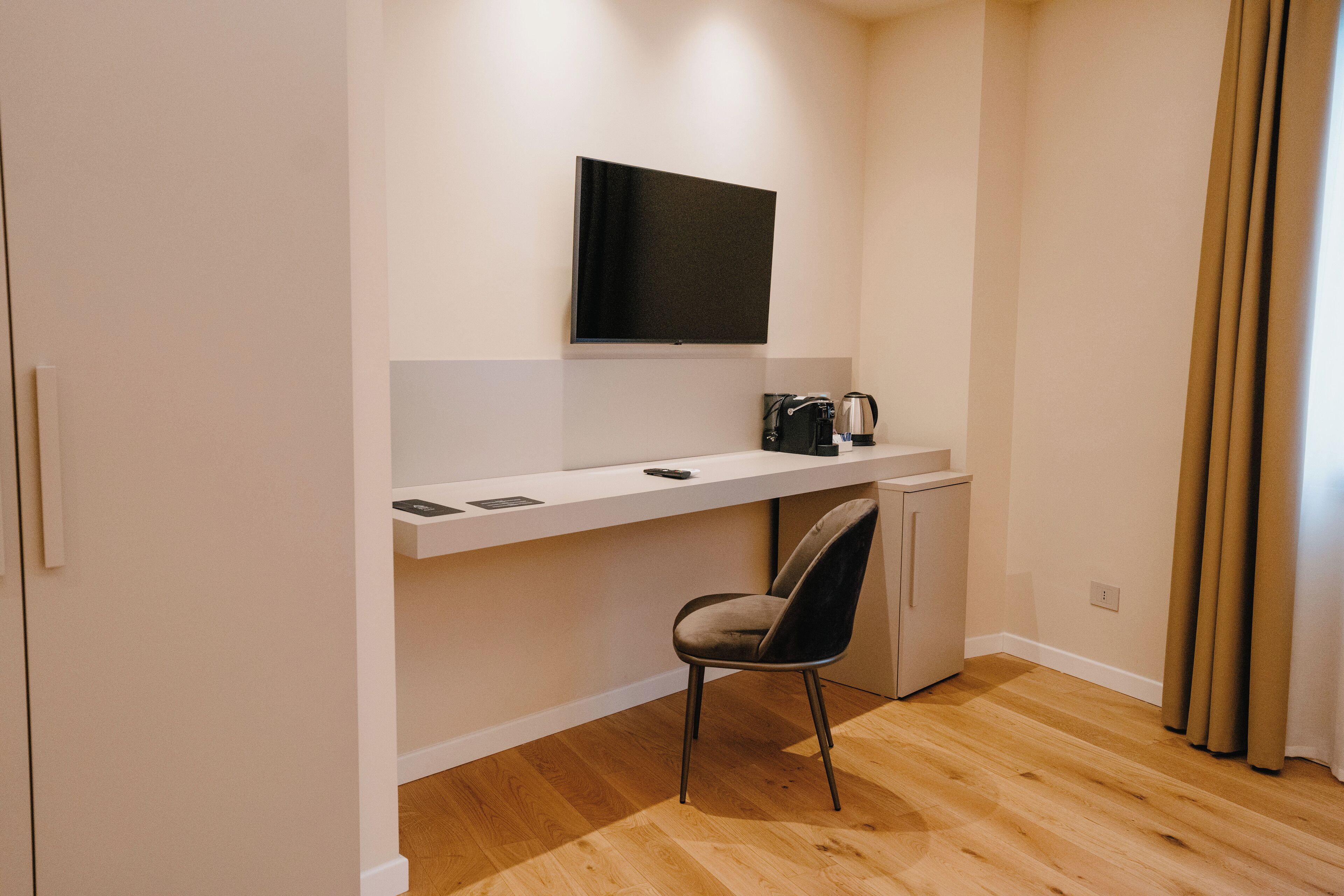 Una habitación moderna con escritorio, silla y televisor de pantalla plana montado en la pared.