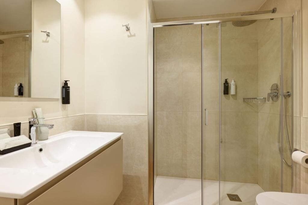 Une salle de bain moderne avec une douche à parois de verre, un lavabo blanc et un grand miroir.
