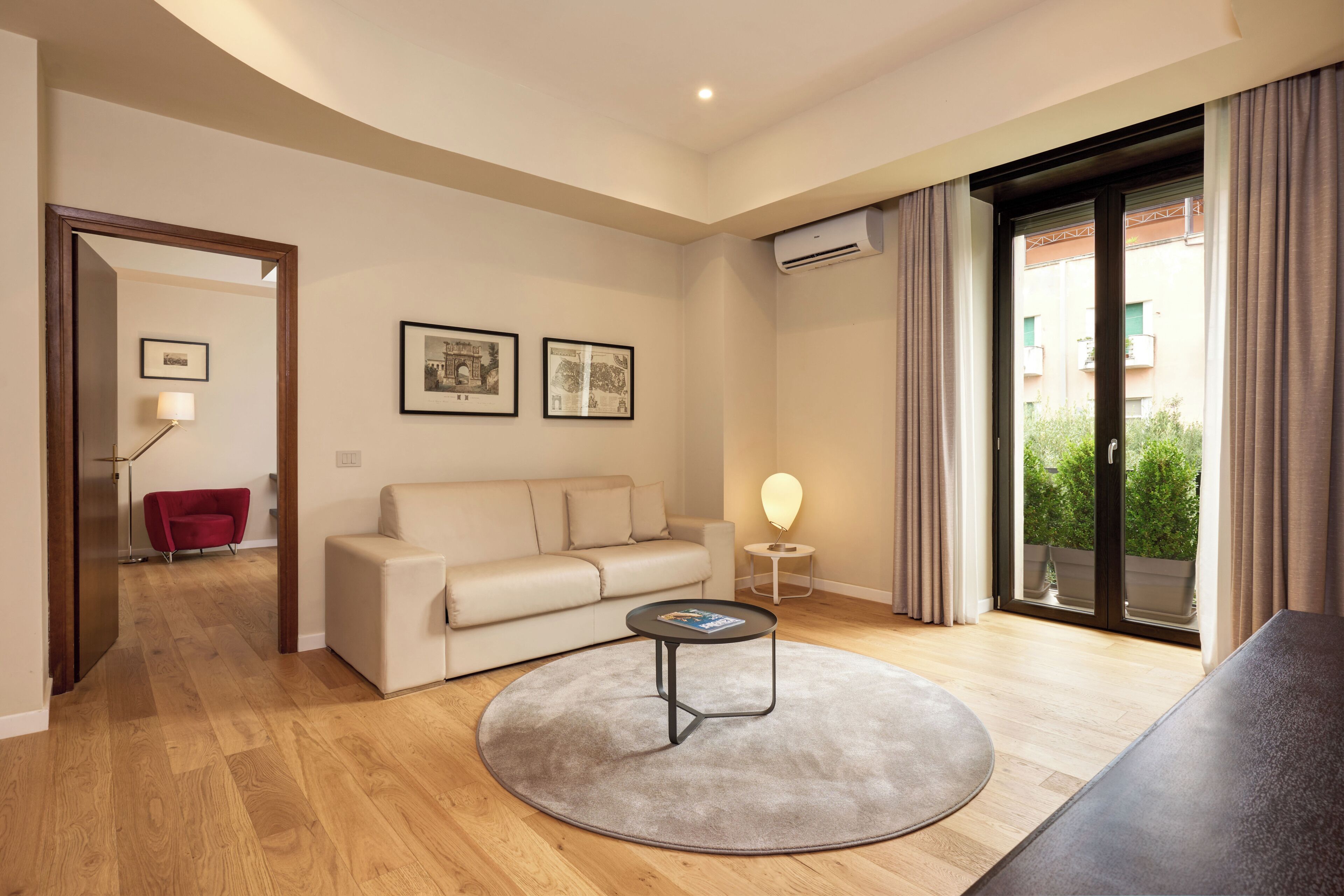A modern living room with a beige sofa, a round coffee table, and two framed pictures on the wall.
