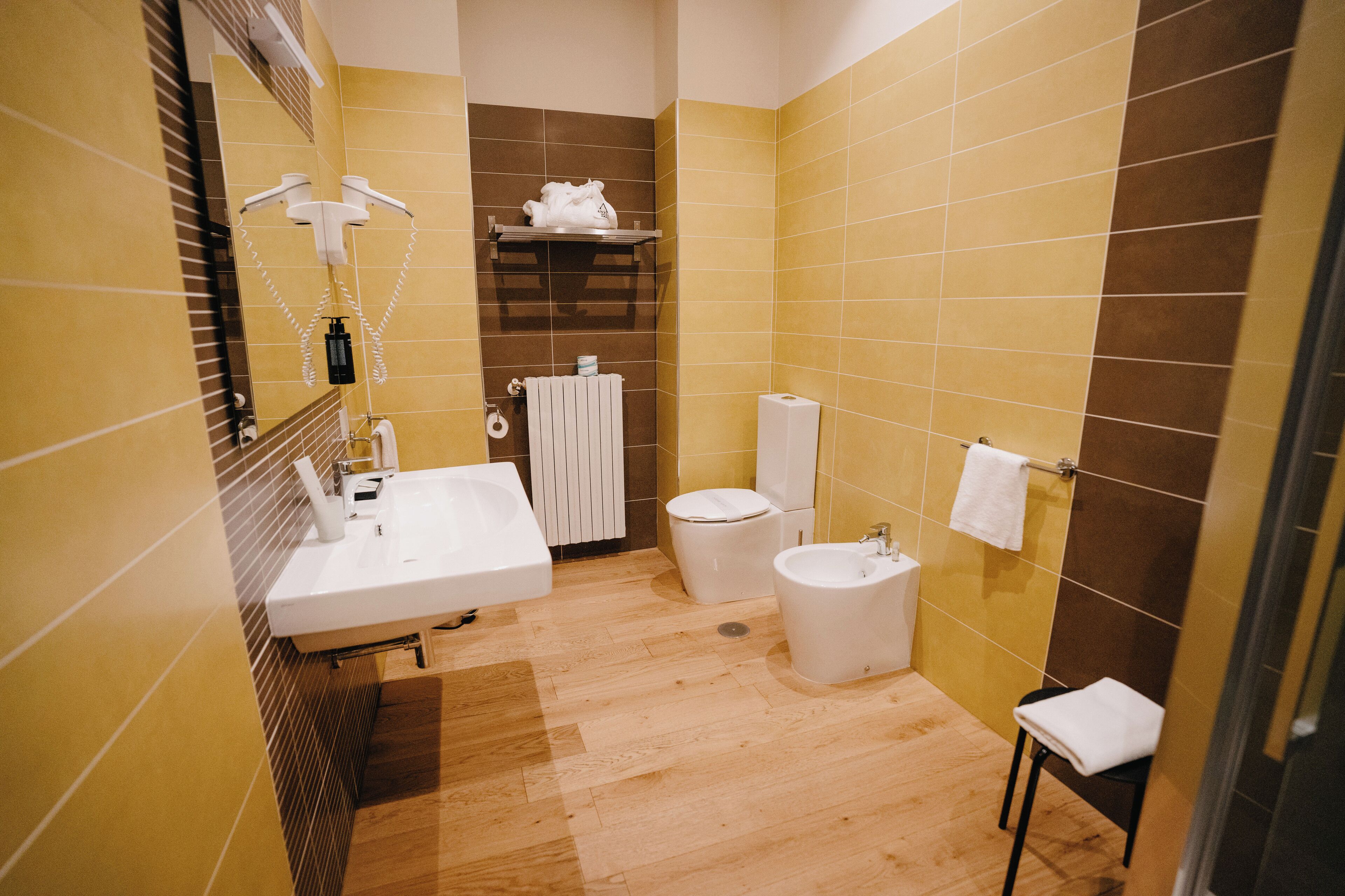 A bathroom with a sink, toilet, bidet, and towel rack.