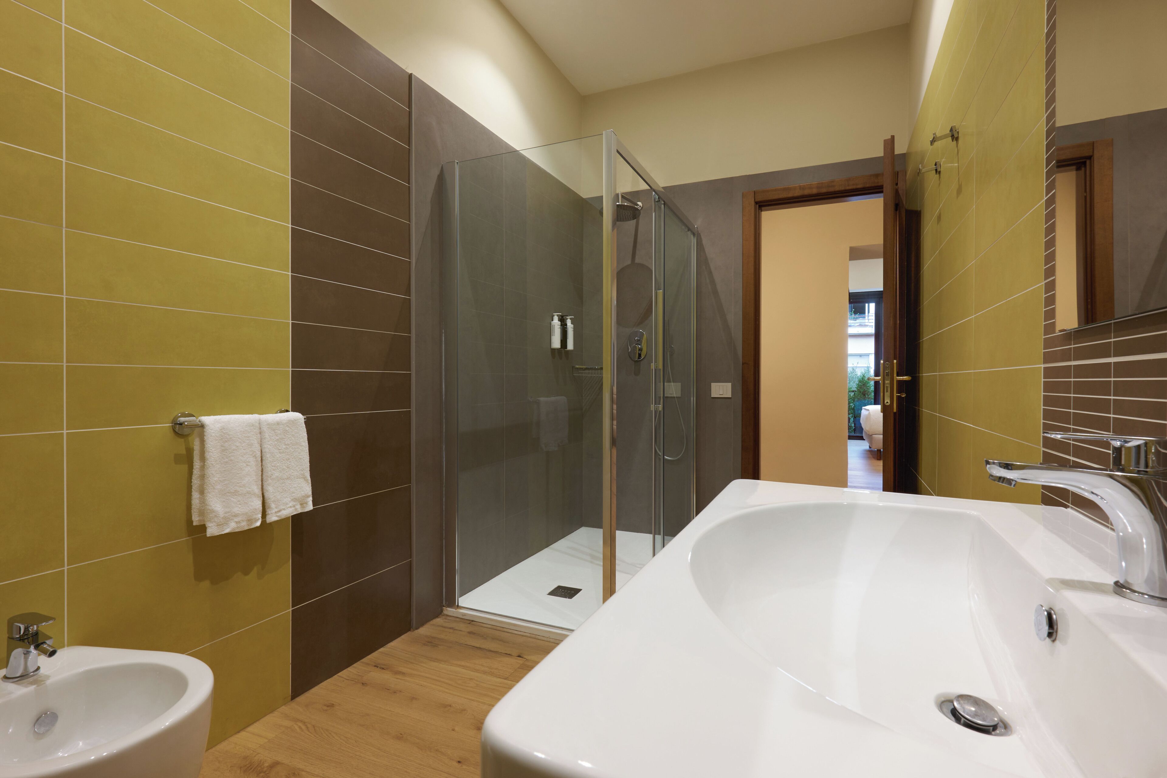 A modern bathroom with a glass shower enclosure, a large white bathtub, and a sink.