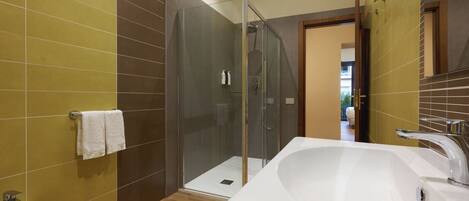 A modern bathroom with a glass shower enclosure, a large white bathtub, and a sink.
