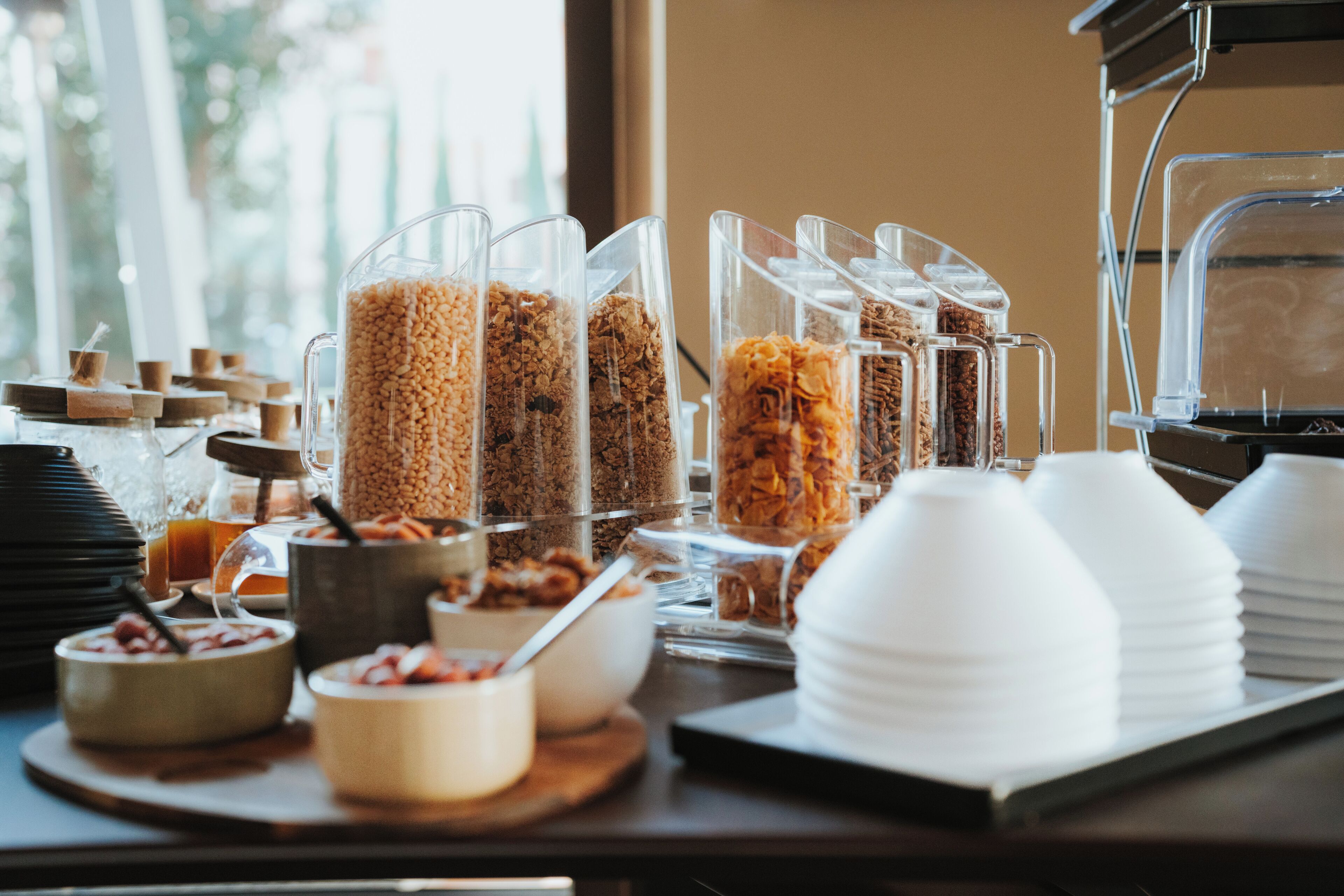 Un buffet della colazione con diverse opzioni alimentari e contenitori di plastica trasparente.