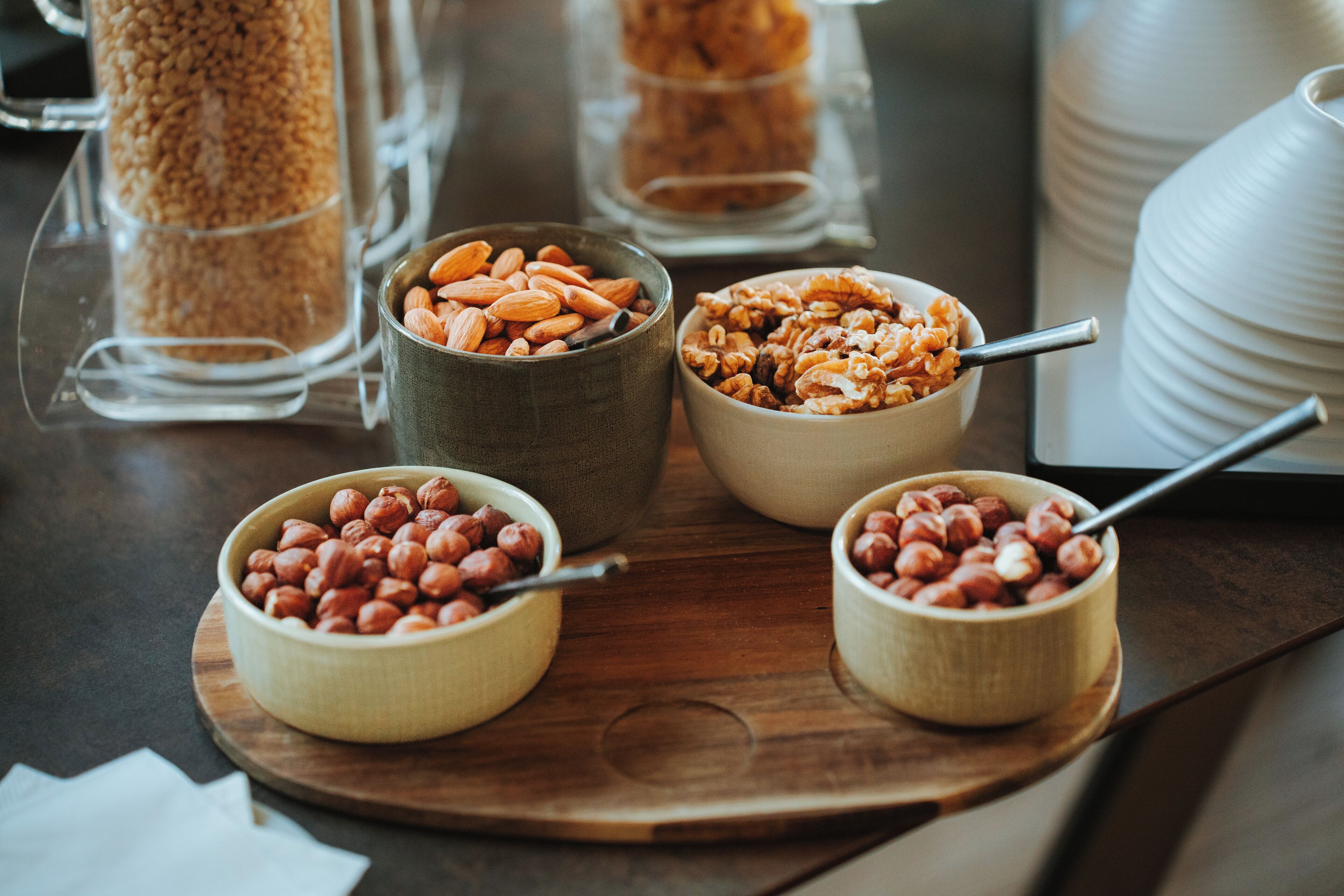 Four bowls of nuts on a wooden board.