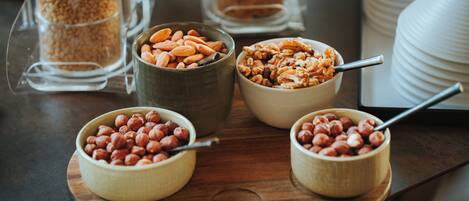 Four bowls of nuts on a wooden board.