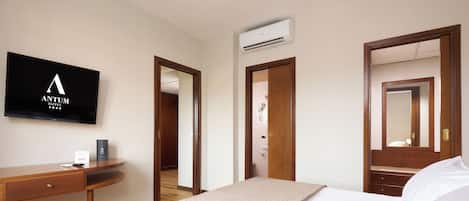 Una habitación de hotel con cama, escritorio, televisor y puerta de baño.