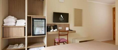 A hotel room with a bed, a wardrobe, a desk with a computer, a chair, and a television.