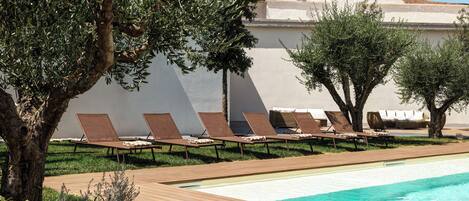 Un área junto a la piscina con sillas de descanso y una piscina.