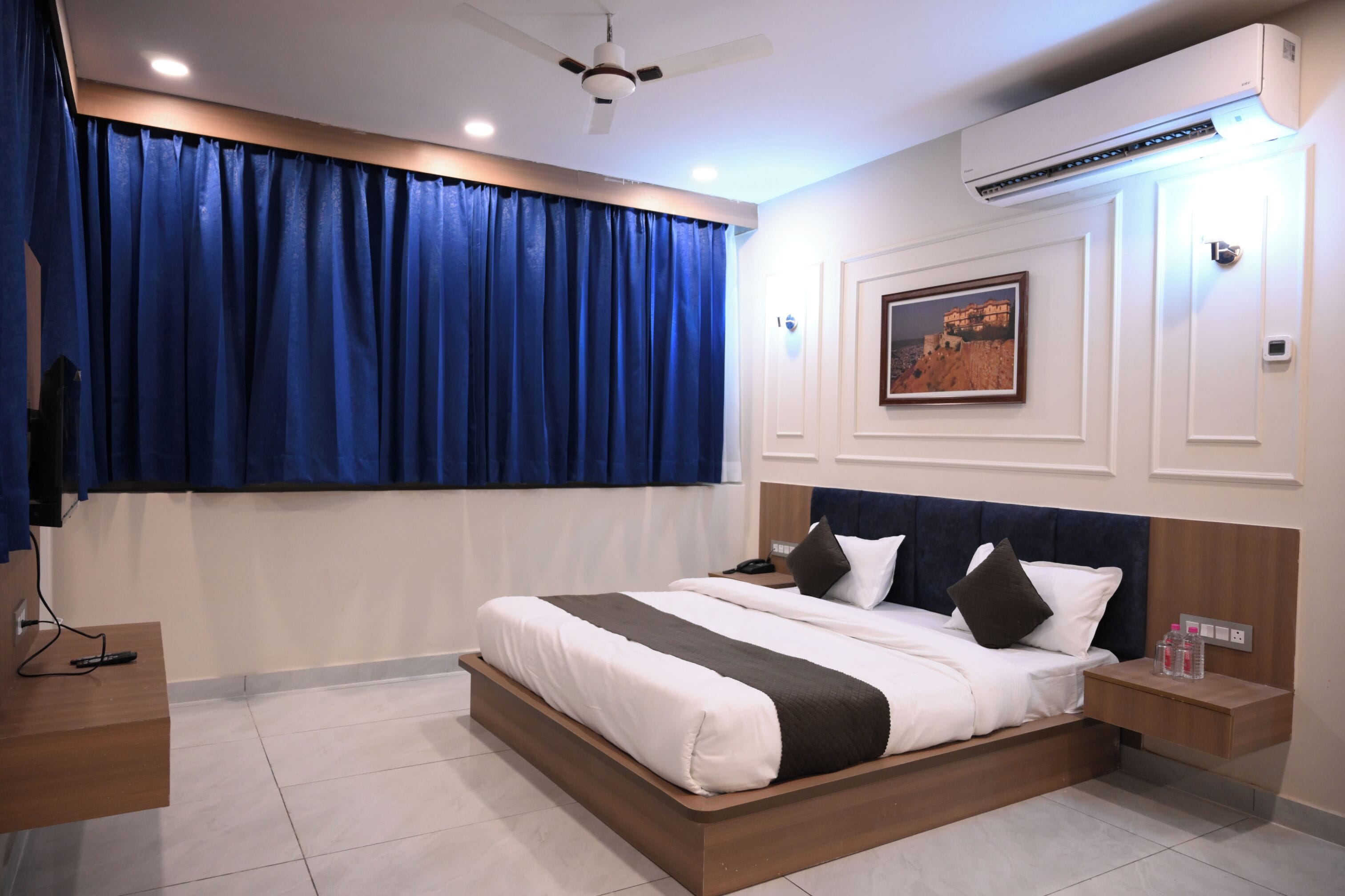 Una camera da letto moderna con un letto grande, un comodino, una ventola a soffitto e un condizionatore d'aria a parete.