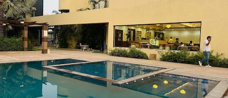 A swimming pool with a clear view of a restaurant and outdoor seating area.