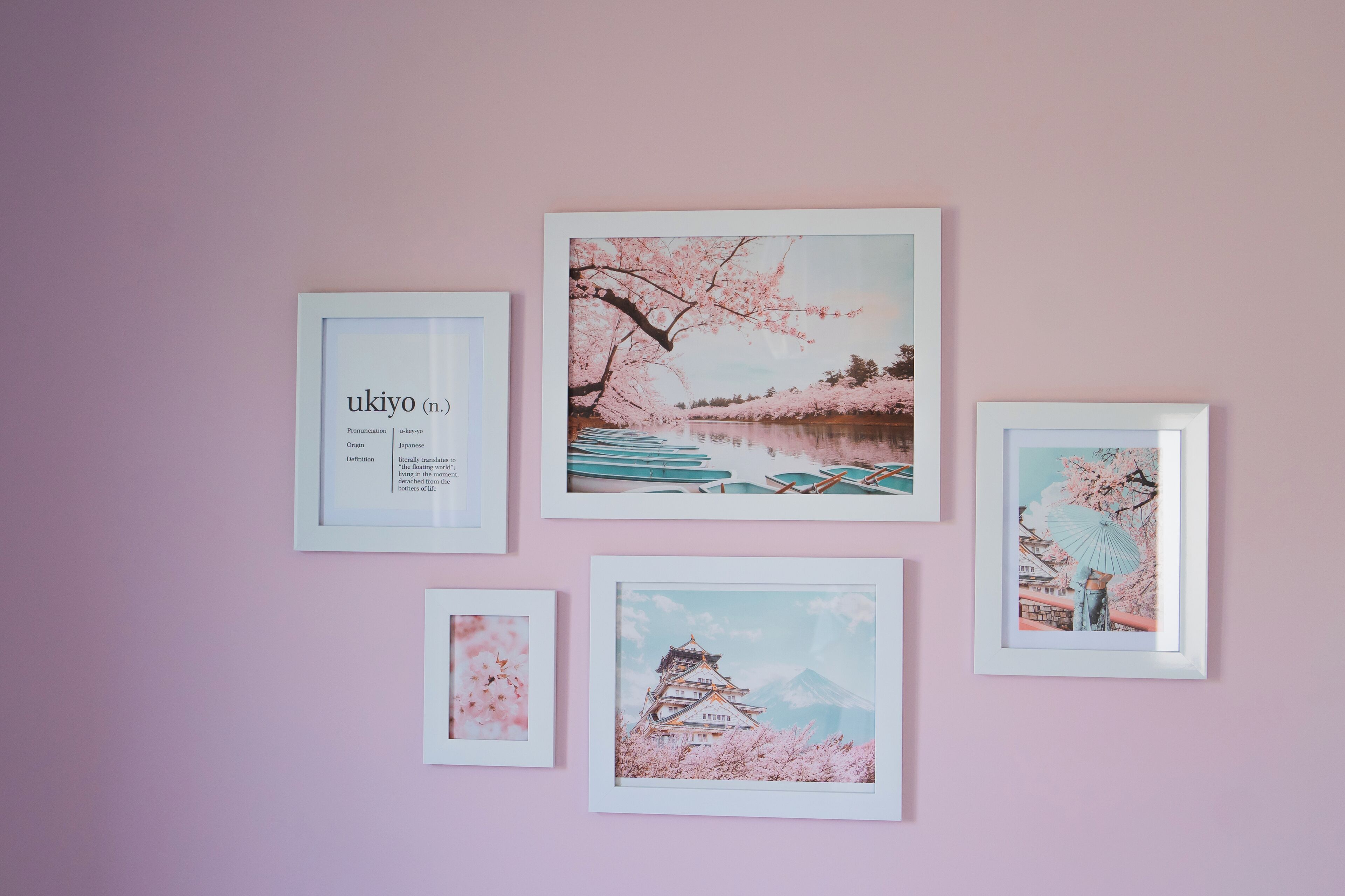 Eine Wand mit fünf gerahmten Bildern, darunter eine Definition von 'ukiyo' und verschiedene Kunstwerke mit japanischem Thema.