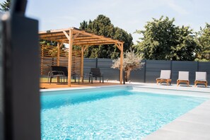A swimming pool with lounge chairs and a wooden pergola. - Résidence des Sables (Mably)