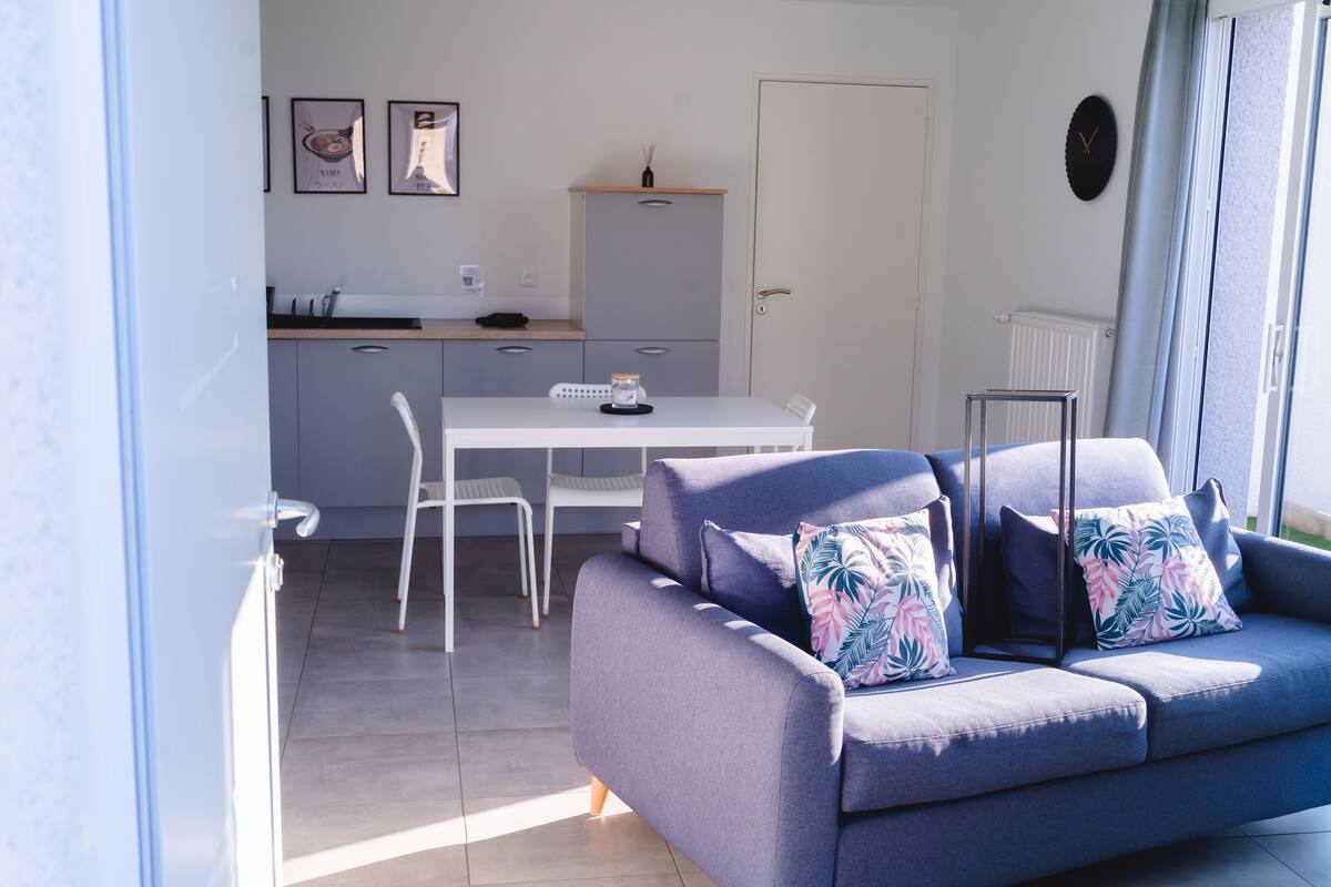 A modern living room with a grey sofa and a dining table.