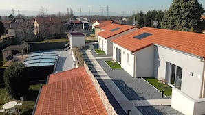 A row of modern houses with red-tiled roofs, a covered patio area, and a view of power lines in the distance. - Résidence des Sables (Mably)