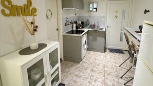 A compact kitchen with white cabinets, a built-in oven, and a sink. - Comfortable 2-room apartment, independent access & PMR. (Épinay-sur-Seine)