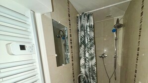 A bathroom with a shower, a sink, and a mirror. - Comfortable 2-room apartment, independent access & PMR. (Épinay-sur-Seine)