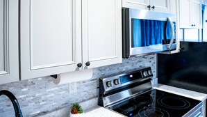 A modern kitchen with white cabinetry, a stainless steel oven, a microwave, and a built-in stove. - Palmer Suite 101, Hyland Hotel (Palmer)