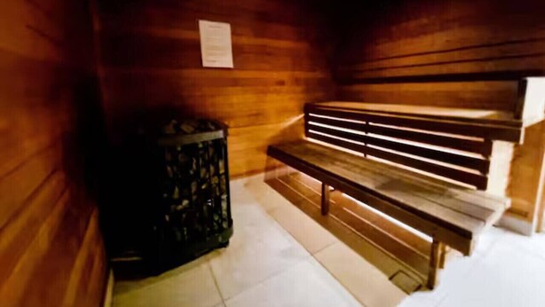A wooden sauna room with benches and a trash bin. - Stylish Arts Apt | Lift | Gym | Sauna (Southbank)