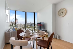 A modern dining area with a city view, a television, and a clock on the wall. - Amalfi Chic | Pool | Gym | Sauna (Southbank)