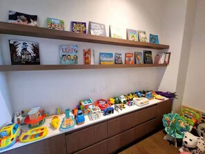 Ein Kinderspielbereich mit Spielzeug und Büchern auf Regalen.