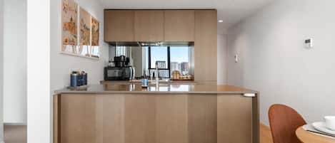 A modern kitchen with a central island, wooden cabinets, and a dining area with a table and chairs.