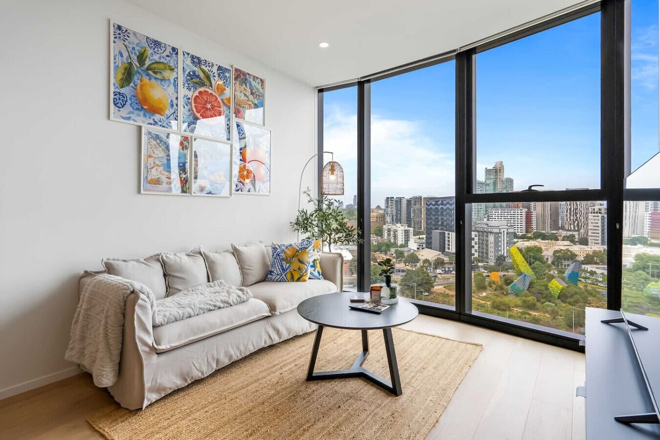 A modern living room with a large window, a sofa, a coffee table, and city views.