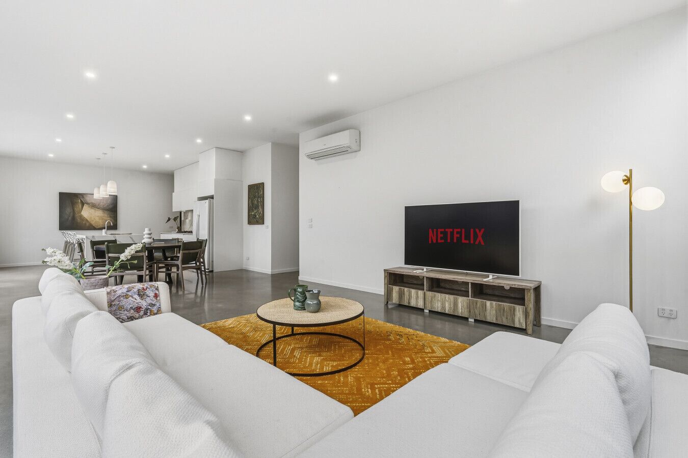 Un salon moderne comprenant un canapé, une table basse, un téléviseur et un coin repas avec des chaises et une table.