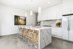 A modern kitchen with a marble island, stainless steel appliances, and pendant lighting. - Donatella, Where Heritage Meets Haute Living (Bendigo)