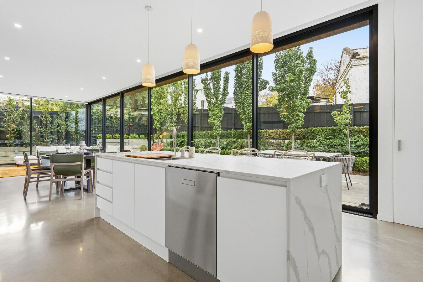 Una cocina moderna con una isla grande, electrodomésticos de acero inoxidable e iluminación colgante.