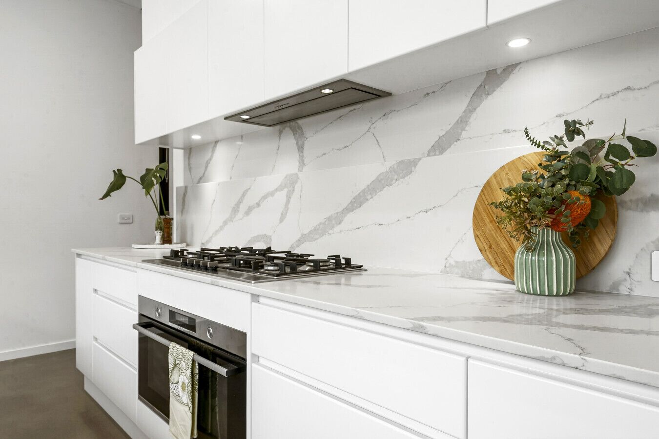 A modern kitchen with a gas stove, oven, and marble backsplash.